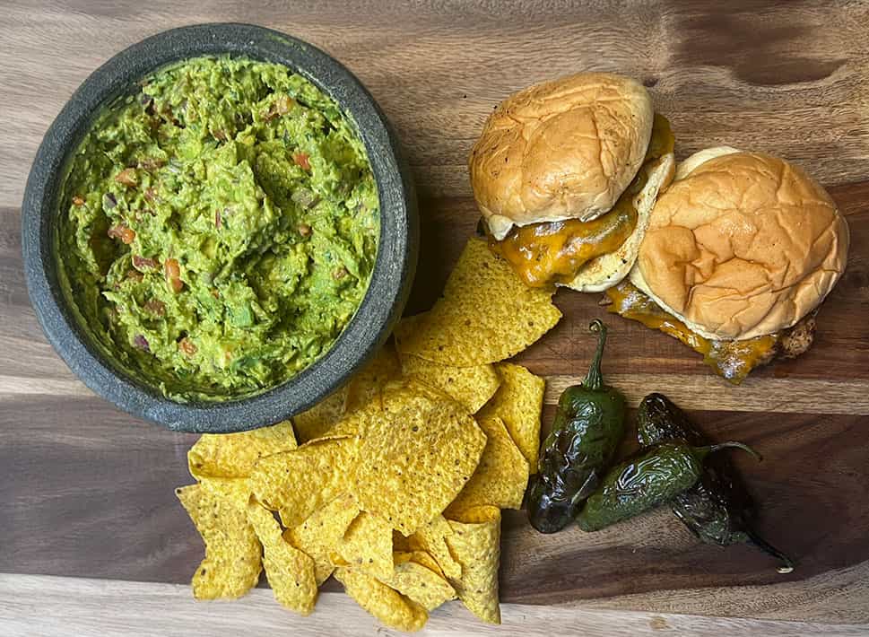 Platter of Southwest Chicken sandwiches with guacamole, corn tortilla chips, and grilled jalapeños
