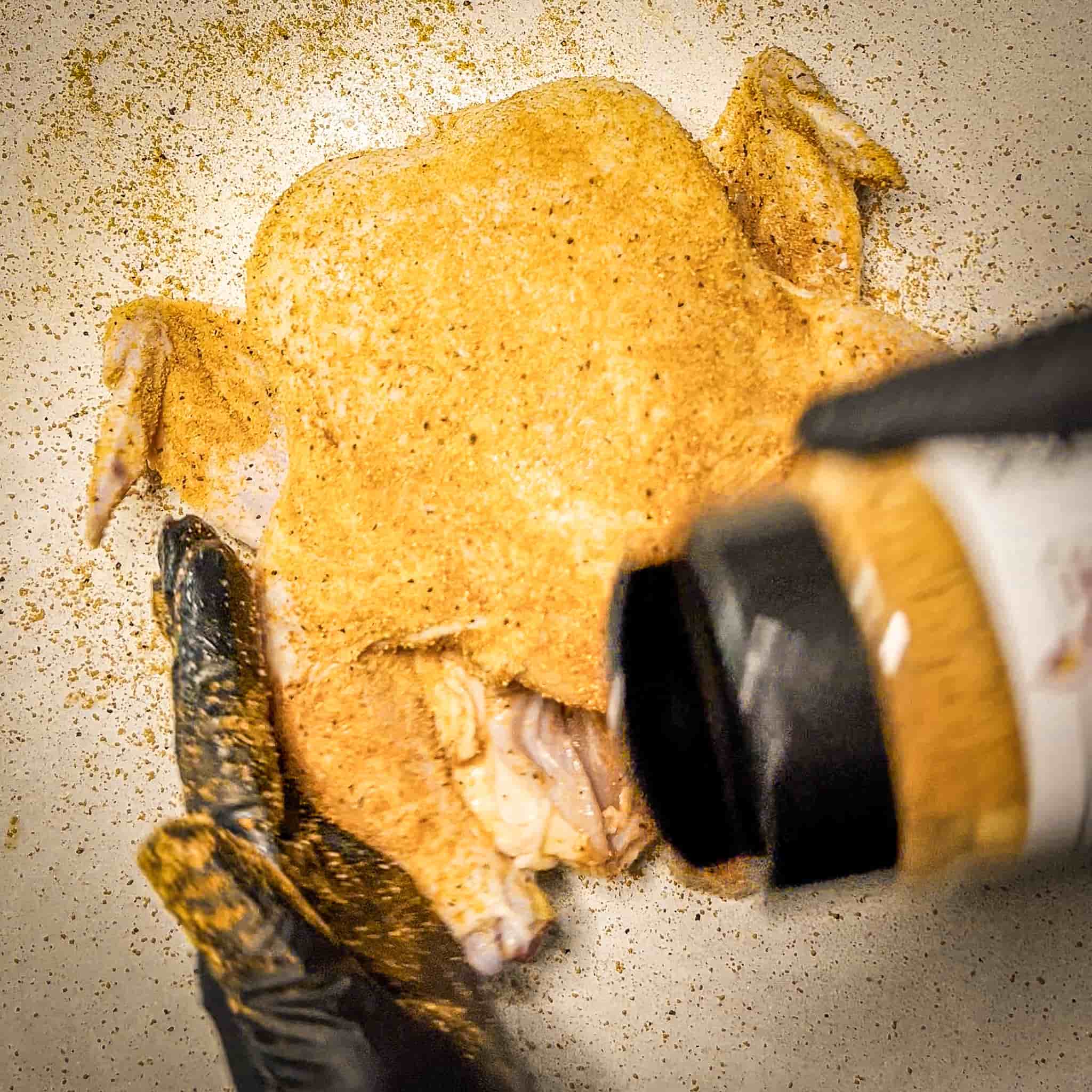 Whole chicken prepped and being seasoned with Sure Fire BBQ Chicken Charmer Rub