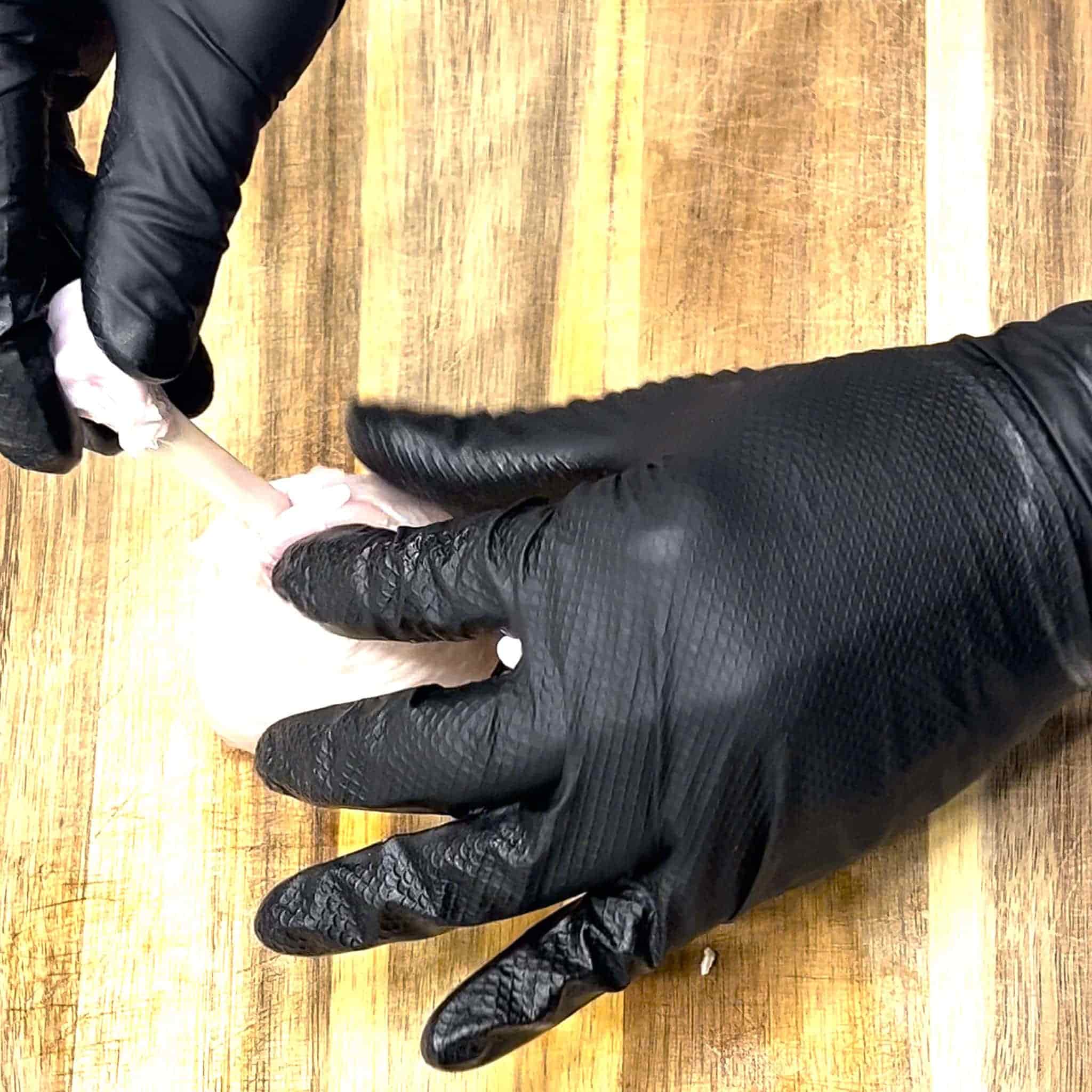 Lollipop drumsticks being prepped by cutting the skin and pushing down to form the lollipop