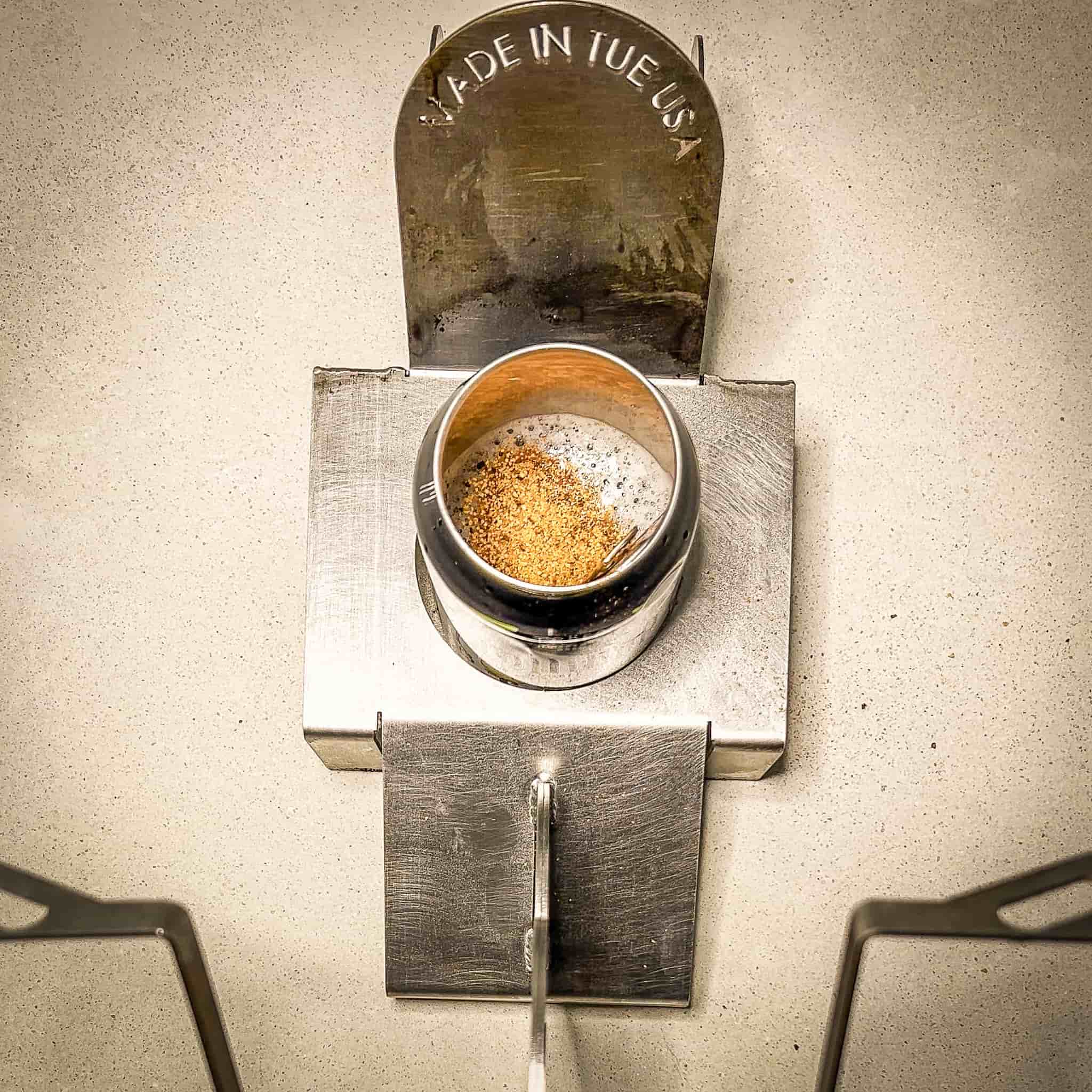 Beer can half full with additional seasoning added and sitting in motorcycle beer can chicken holder